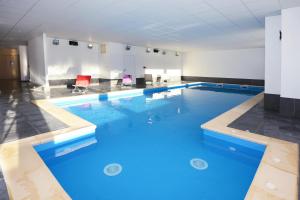 una grande piscina con acqua blu in un edificio di Résidence Odalys Les Balcons d'Auréa ad Auris