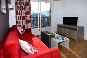 a living room with a red couch and a television at Résidence Odalys Les Balcons d'Auréa in Auris