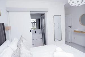 Un dormitorio blanco con una cama y un espejo. en Gonubie Beachside Delight, en East London