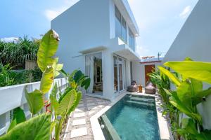 a villa with a swimming pool in front of a house at Lyma Loft Pererenan in Canggu