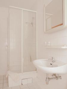 a white bathroom with a sink and a shower at Hotel zur Sonne in Cottbus