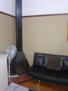 Sofá negro en una habitación con ventilador en Room Parow, Cape Town, en Cape Town