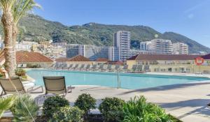 Una piscina con sillas y una ciudad. en Carrara Eurocity - Luxury Family Apartment with Resort Style Pool - Children stay for Free, en Gibraltar