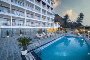 a hotel with a swimming pool in front of a building at KC Vilaas Kufri in Kūfrī