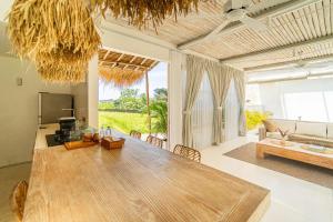 una sala de estar con una gran mesa de madera y un sofá en Kokomo Villas by Aayan, en Canggu