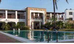 a house with a swimming pool in front of a building at Hayce Residence Ocean View Apartment in Kilifi