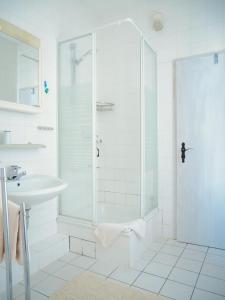 a white bathroom with a shower and a sink at Hotel zur Sonne in Cottbus