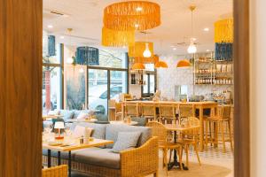 a restaurant with tables and chairs and yellow chandeliers at Bikube Coliving Hôtel - Lyon Centre Lumière in Lyon