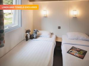 dos camas con animales de peluche sentados en una habitación en Camping Le Ty Nadan - Roan, en Quimperlé