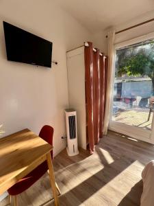 ein Wohnzimmer mit einem Tisch und einem Fernseher an der Wand in der Unterkunft Studio paisible dans un quartier calme in Marguerittes