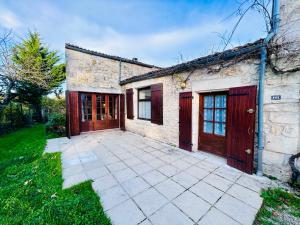 a brick house with red doors and a patio at L'Envol - Spacieuse maison avec piscine privative in Champagne