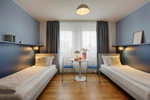 zwei Betten in einem Zimmer mit einem Tisch in der Unterkunft homie hotel max apart - Fürth in Fürth + 29 Fotos
