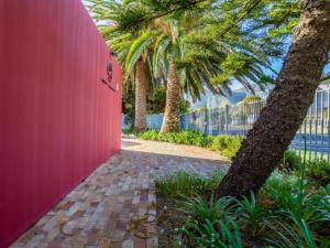 a pink wall with palm trees and a sidewalk at Two Palm House - Vermont Hermanus in Hermanus +4 photos