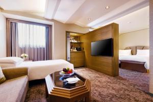 a hotel room with two beds and a flat screen tv at The Landis Taipei in Taipei