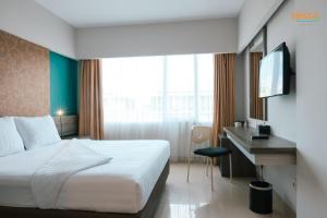 a hotel room with a bed and a desk and a television at Siesta Legian in Legian
