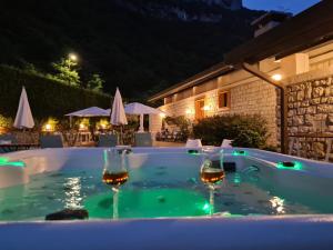 two wine glasses in a swimming pool at night at Villa degli Olivi Relais in Nago-Torbole
