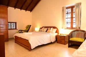a bedroom with a bed and a chair and a window at Ederra Stays & Cafe in Panaji