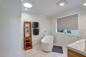 a bathroom with a tub and a sink and a window at Lumeah by the Creek in Whian Whian +30 photos