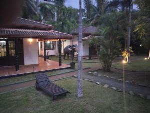 an elephant standing in front of a house with a bench at New Coco cabana in Bentota