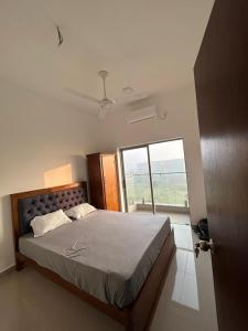 ein Schlafzimmer mit einem Bett und einem großen Fenster in der Unterkunft Canterbury Golf Resort Apartments and Residencies by Home Lands Skyline in Gonapola