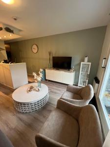 a living room with couches and a table and a tv at Appartement Noflik, Amelander Kaap in Hollum