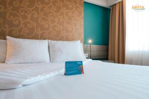 a white bed with a blue sign on it at Siesta Legian in Legian