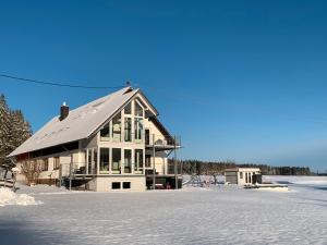 une grande maison avec toit dans la neige dans l'établissement Naturzeit, à Königsfeld im Schwarzwald