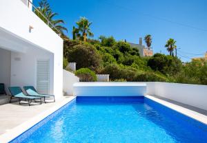 une piscine avec deux chaises à côté d'une maison dans l'établissement Casa Cubo - Amazing Central 6 bedroom Villa, à Carvoeiro