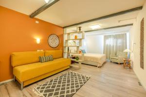 a living room with a yellow couch and a bedroom at IBEX unique Desert Inn in Mitzpe Ramon