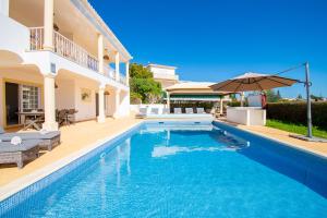 a villa with a swimming pool and an umbrella at Casa Filipa Lower Floor - Charming 3-Bedroom Villa with Heated Pool in Praia do Carvoeiro