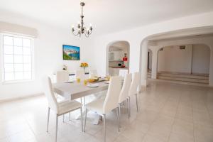a white dining room with a table and white chairs at Casa Filipa Lower Floor - Charming 3-Bedroom Villa with Heated Pool in Praia do Carvoeiro