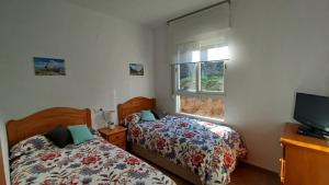 a bedroom with two beds and a tv and a window at Apartamento Montanejos in Montanejos