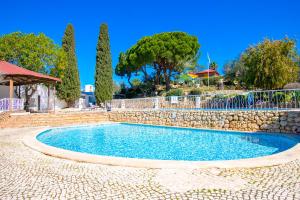 ein Swimmingpool mit einer Steinmauer und Bäumen in der Unterkunft C65 Quinta do Paraiso - Charming 2-Bedroom Bungalow in Carvoeiro