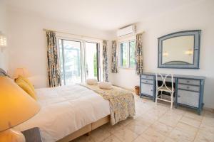 ein Schlafzimmer mit einem Bett, einem Spiegel und einem Stuhl in der Unterkunft Casa Miguel - Family-Friendly 3-Bedroom Villa with Private Pool in Benagil + 37 Fotos