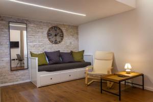 a living room with a couch and a clock on a wall at Hero Square Condo in Budapest