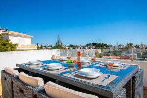 a table with plates and wine glasses on a balcony at Casa Filipa Full house - Spacious Villa with Private Pool & Jacuzzi in Praia do Carvoeiro