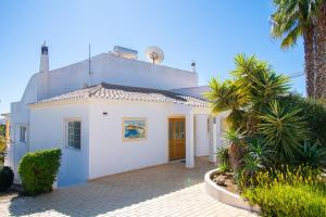 a white house with palm trees in front of it at Casa Filipa Full house - Spacious Villa with Private Pool & Jacuzzi in Praia do Carvoeiro