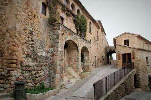 an old stone building with an alleyway and a fence at Casa Pueblo Medieval de Pals in Pals