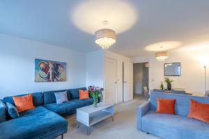 a living room with blue couches and orange pillows at Rolls Royce View - 2 Bed House Sleeps 6 near Goodwood, Witterings and Rolls Royce Factory in Chichester