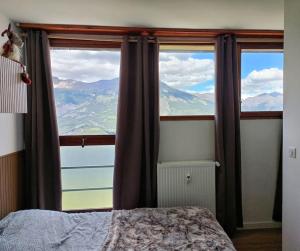 a bedroom with a window with a view of the mountains at Duplex de montagne 4 personnes in Uvernet