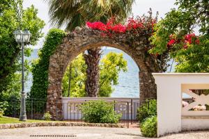 an archway with red flowers on it in front of the water at Villa Irlanda Grand Hotel in Gaeta
