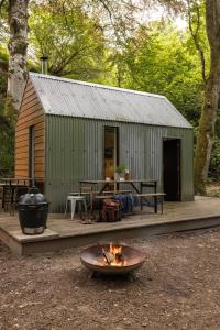 a fire pit in front of a cabin with a grill at North Lodge & River Cabin in Banchory
