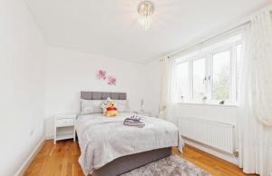 a white bedroom with a teddy bear sitting on a bed at Beautiful Family Town Home With Private Parking in Canterbury