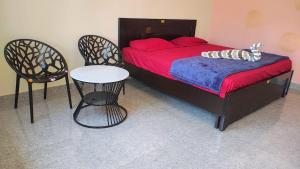 ein Schlafzimmer mit einem Bett und zwei Stühlen und einem Tisch in der Unterkunft Roopa Resorts in Araku