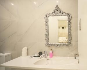a white bathroom with a sink and a mirror at Sliema Central Iprime Suites in Sliema