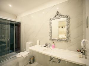 a white bathroom with a sink and a mirror at Sliema Central Iprime Suites in Sliema