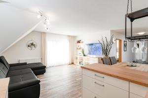 a living room with a black couch and a kitchen at Landhotel Kirchberg - Hotel Garni in Kirchberg an der Jagst