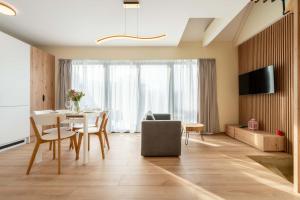 a living room with a table and chairs and a television at Apartamenty Słoneczne Tarasy z widokiem na góry - Dream Apart in Szczyrk