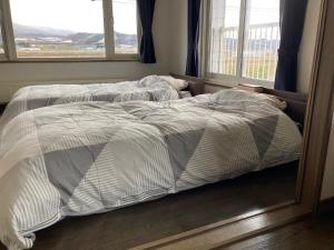 2 letti non fatti in una camera da letto con due finestre di countryside FURANO a Nakafurano