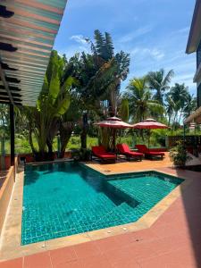a swimming pool with chairs and umbrellas in a resort at Love Room - Center Thong Sala - Swimming Pool in Thongsala